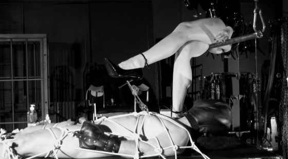 Slave lying on the bondage table, strictly fixed with tight ropes